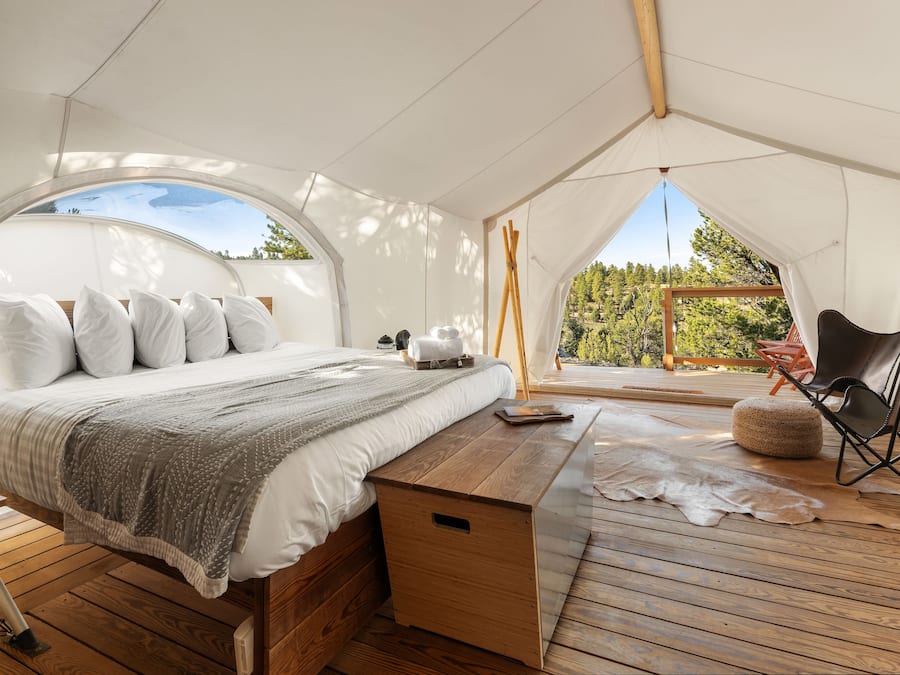 Una habitación con carpa, una cama, un banco de madera y una silla.