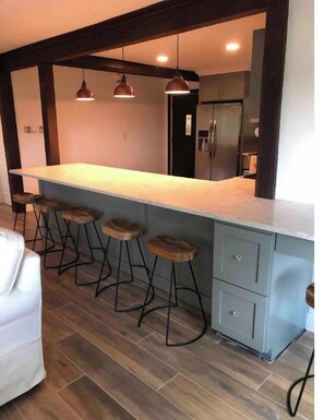 Cozinha moderna com bancada, banquetas de madeira e geladeira embutida.