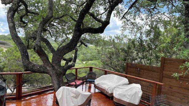 A covered outdoor seating area with two sofas and a table, surrounded by a wooden deck and a large tree. - Hop/Skip/Jump to Canyon Lake - 3 BR, 2 Bath (Canyon Lake)