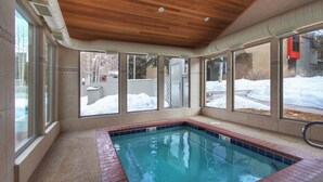 Une piscine extérieure couverte, dotée d’un plafond en bois et de grandes fenêtres.