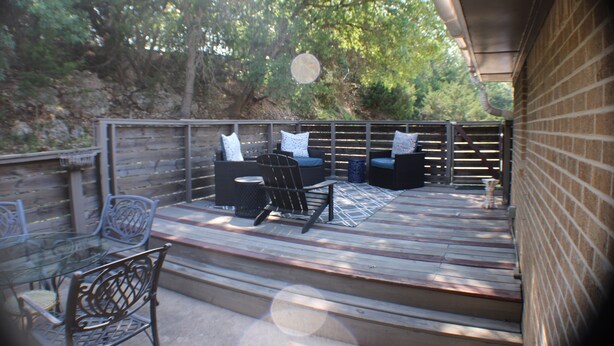 A wooden deck with outdoor furniture, including a sofa and chairs, overlooking a wooded area. - The View at 5 Hills (Copperas Cove)
