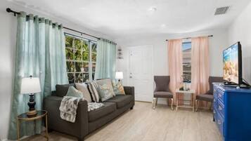 A living room with a sofa, a chair, a TV, and a small table.