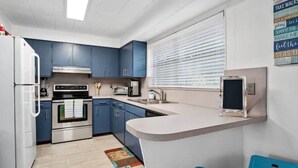 A modern kitchen with blue cabinets, a built-in oven, a microwave, and a sink. - King Bed Near Pickleball, Beach & Downtown (Naples)