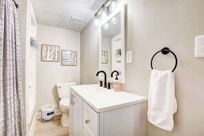 A bathroom with a white sink, black faucet, and a towel ring on the wall. - Garden Cottage · Garden Cottage - Fire Pit and Grill near Beaches (Lusby)