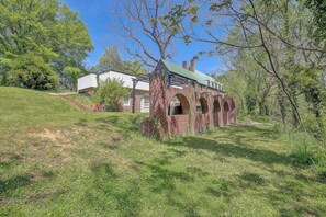 A brick structure with arches, surrounded by grass and trees.