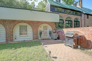 A brick house with a covered patio, a grill, and a small garden.
