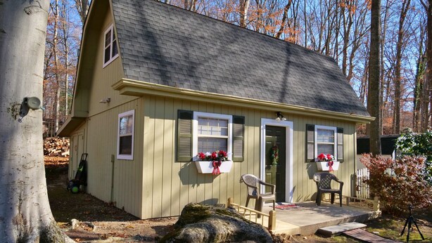 A small, single-story house with a sloped roof, a front porch with two chairs, and a small deck. - The Wright Place (Kingsport)