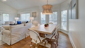 A spacious dining area with a wooden table and white wicker chairs, a ceiling fan, and a hanging light fixture. - FREE GOLF CART. private HEATED pool option. Walk to the beach.Sleeps 10! (Destin)