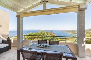Relax in style with a scenic view of the sea and distant hills from this outdoor seating area.