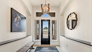 A hallway with a bench, a rug, a chandelier, a framed picture, and a mirror. - ** NEW 5 STAR HILL COUNTRY RETREAT ** (Dripping Springs)