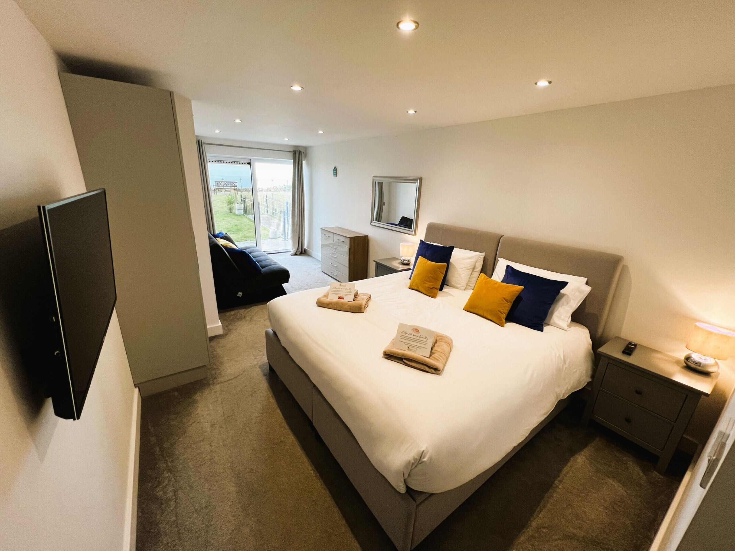 A hotel room with a large bed, a TV, a desk, and a view of the outdoors.
