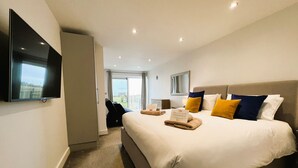 Une chambre d’hôtel moderne dotée d’un grand lit, d’une télévision à écran plat et offrant une vue sur l’extérieur.