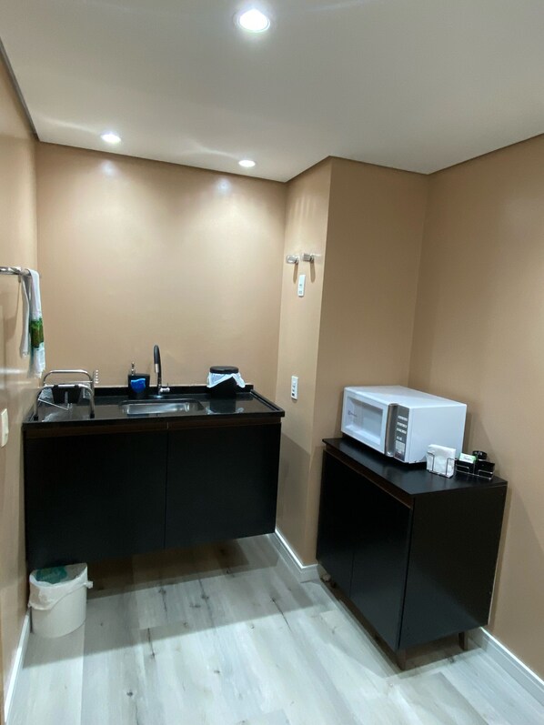 A small kitchenette with a microwave, sink, and a small cabinet.