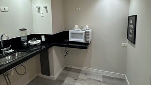 A modern kitchen with a black countertop, a built-in microwave, and a sink. - Cozy apartment with modern design - Sol Alphaville Hotel & Residence (Barueri)