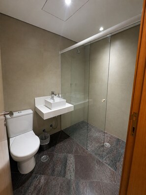 A modern bathroom with a toilet, sink, and glass shower enclosure. - Cozy apartment with modern design - Sol Alphaville Hotel & Residence (Barueri)