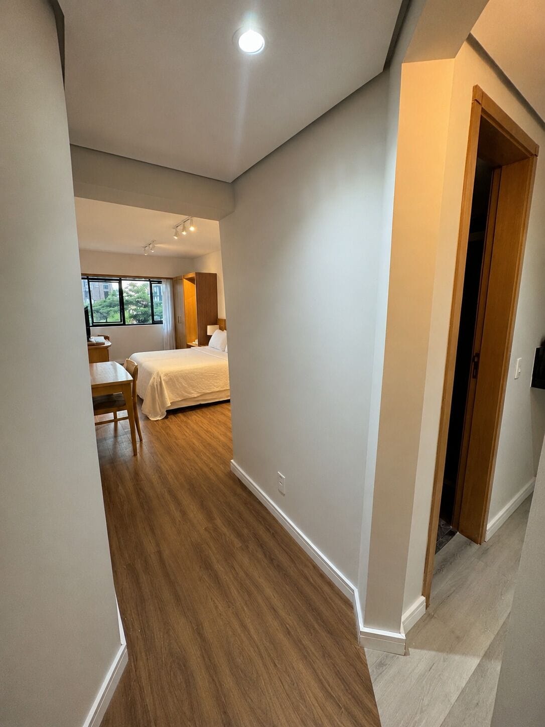 A hotel room with a bed, bedside table, and a window.