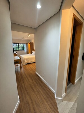 A hotel room with a bed, bedside table, and a window.