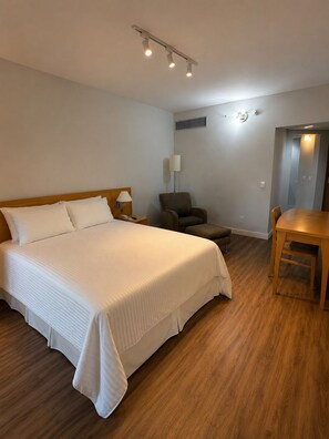 A hotel room with a large bed, a chair, a table, and a desk.