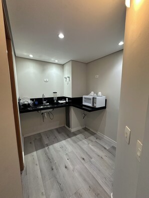 A modern kitchen with a black countertop, white appliances, and a wooden floor.