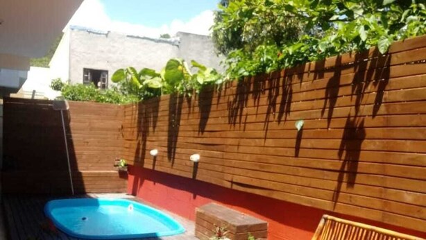 A wooden deck with a hot tub, a bench, and potted plants.