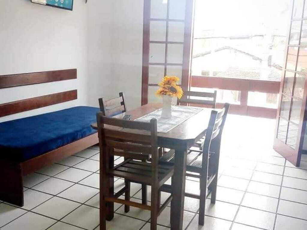 A room with a dining table, chairs, a blue sofa, and a window with a view of buildings.