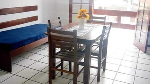 A room with a dining table, chairs, a blue sofa, and a window with a view of buildings.