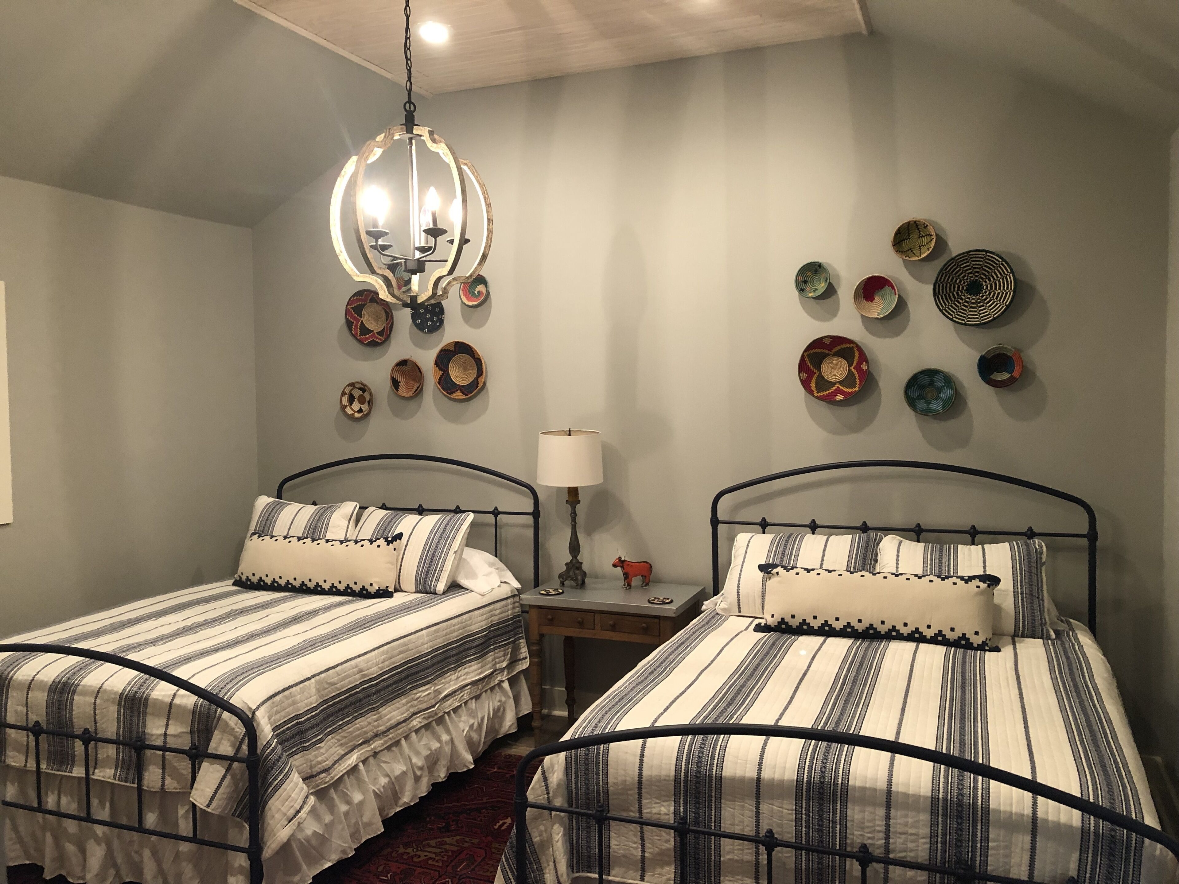 A bedroom with two beds, a chandelier, and wall decor.