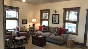 A cozy living room with a sofa, armchairs, a coffee table, and a fireplace. - SunShiner Farm - Shiner, TX (Shiner)