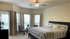 A bedroom with a bed, a desk, a chair, and a ceiling fan.