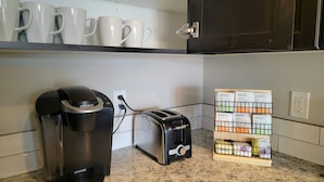 A kitchen with a coffee maker, toaster, and a shelf with coffee pods. - Downtown Hermiston  (Hermiston)