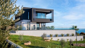 Una casa moderna de dos pisos con un balcón que ofrece vistas a la costa.