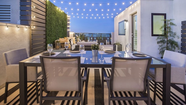 An outdoor dining area with a table set for two, surrounded by chairs, and string lights overhead. - LA Harbor View with Private Rooftop and FREE Tesla Charger (San Pedro)