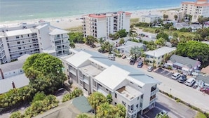 A coastal hotel with multiple buildings, a beach in the background, and a parking area. - Updated condo just steps to the white sand beaches of Clearwater Beach (Clearwater)