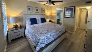 A bedroom with a bed, nightstands, a ceiling fan, and framed artwork on the wall. - Updated condo just steps to the white sand beaches of Clearwater Beach (Clearwater)