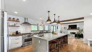 Una cocina moderna con una isla grande, electrodomésticos de acero inoxidable y piso de madera.