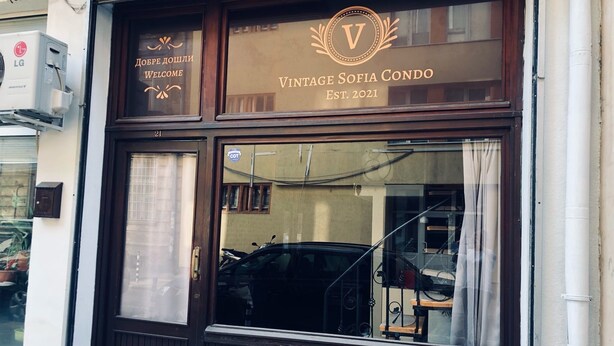 En butiksfasad i gammal stil med ett stort skyltfönster och en skylt med texten "Vintage Sofia Condo, etablerat 2021".