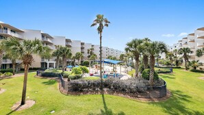 Resort com edifícios de vários andares, um pátio central com palmeiras e áreas de estar ao ar livre.