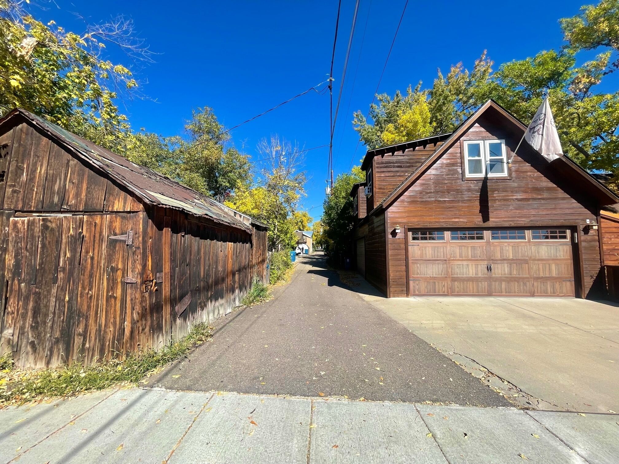 A narrow street flanked by wooden buildings with a garage on the right.