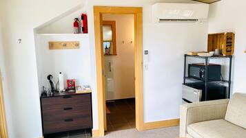 Un espacio habitable pequeño con kitchenette, sofá y techo de madera.
