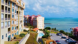 Ein mehrstöckiges Hotel mit Balkonen, einem Swimmingpool und Meerblick.