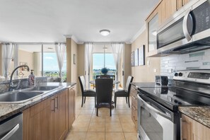 A modern kitchen with granite countertops, stainless steel appliances, and a dining area with a view.