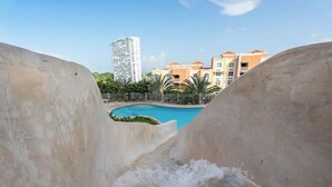 Blick auf ein Schwimmbecken, umgeben von Gebäuden, mit einem hohen Bauwerk im Hintergrund.