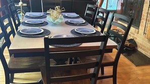 A dining area with a wooden table set for six, surrounded by chairs.