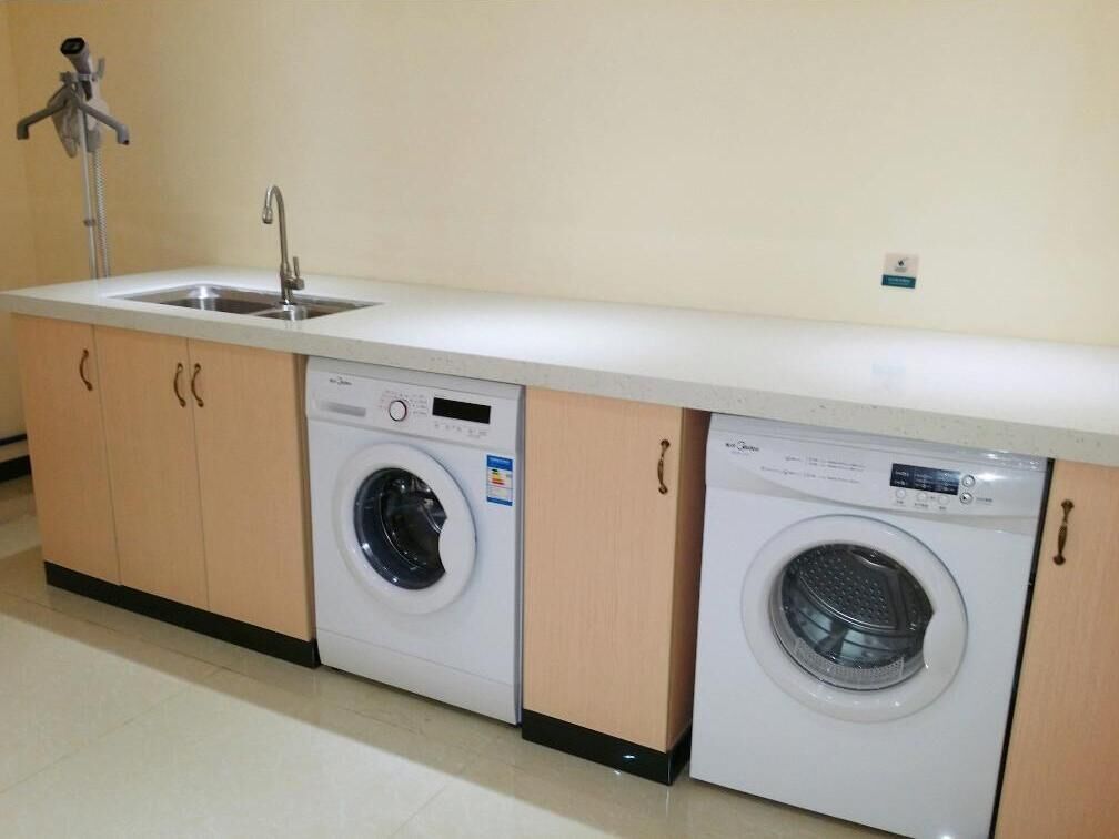 A compact laundry area with two washing machines, a sink, and a faucet.