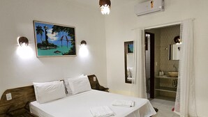 Moderni hotellihuone, jossa on suuri sänky, seinällä taulu ja avoimesta ovesta näkyy kylpyhuone.