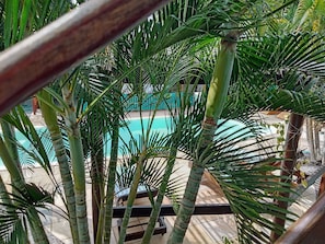 A pool area surrounded by palm trees and a wooden deck. - Hawaii Flats (São Miguel do Gostoso)