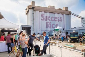 Un grand bâtiment industriel portant l’enseigne « Success Rice », avec des tables à l’extérieur et un camion-restaurant.