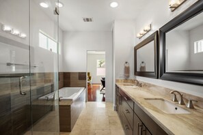 Une salle de bain moderne dotée d’une douche à parois de verre, d’une baignoire sur pieds et d’un meuble-lavabo avec un grand miroir.