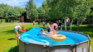 Una piscina inflable con estructura de mimbre, etiquetada como "Bestway Steel Pro MAX", en un área exterior con césped.