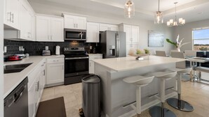 A modern kitchen with white cabinetry, stainless steel appliances, and a central island with bar stools. - Fireworks from Balcony, No Resort Fees! (Kissimmee)